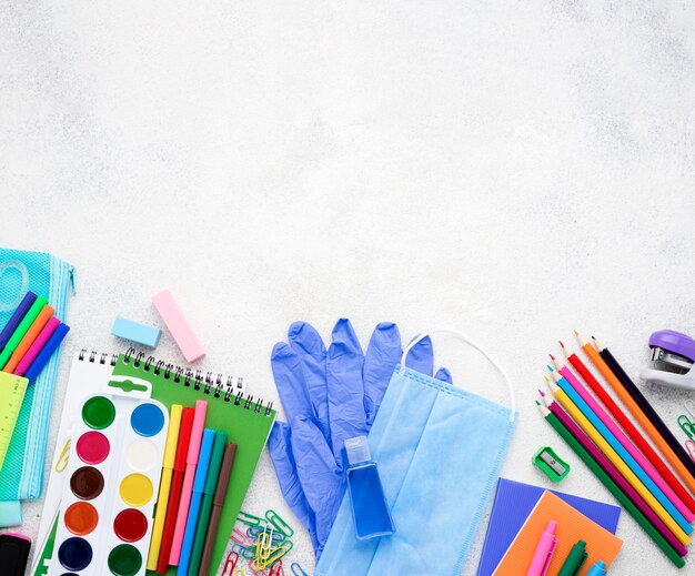 Flat lay of school essentials with notebooks and medical mask