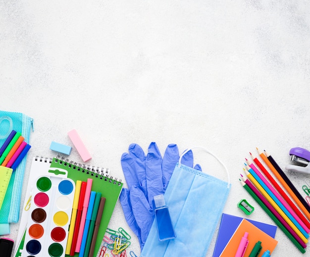 Flat lay of school essentials with notebooks and medical mask