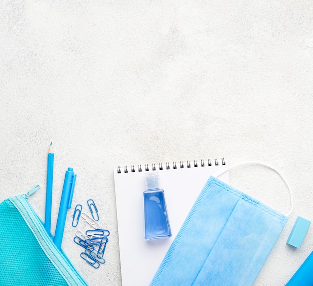 Free photo flat lay of school essentials with paper clips and medical mask