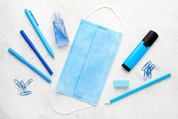 Flat lay of school essentials with pencils and medical mask