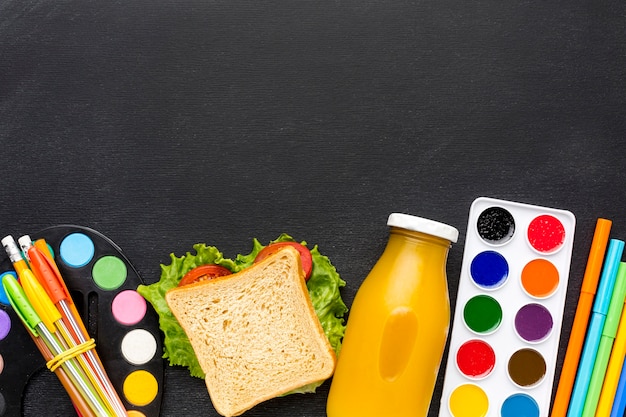 Flat lay of school essentials with sandwich and juice