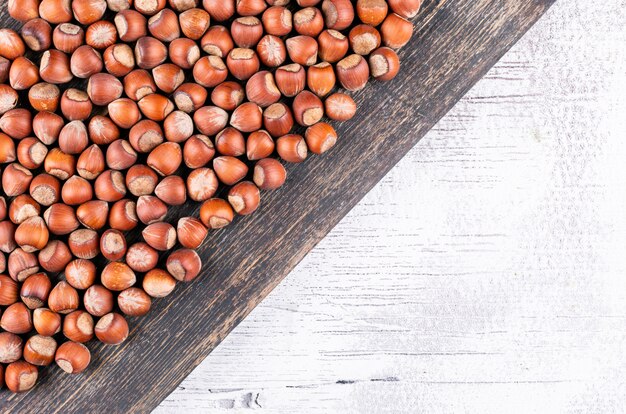 Flat lay shelled hazelnuts on dark and white wooden table.