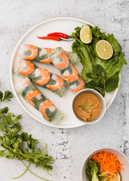 Flat lay of shrimp rolls with sauce and lime