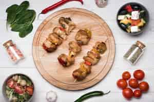 Free photo flat lay skewers on wooden board with ingredients