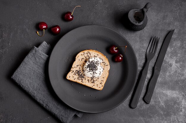Flat lay slice of bread with cream and arrangement of cherries