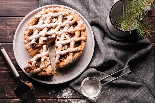 Flat lay of sliced pie with sieve and cloth