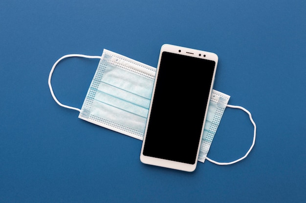 Flat lay of smartphone with medical mask