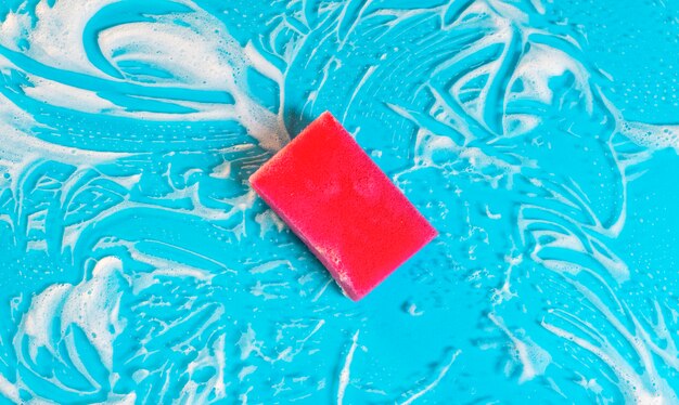 Flat lay soap foam and sponge on blue background