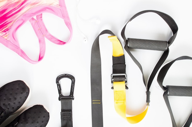 Flat lay of sport equipment, pink sport bra, sneakers on white background. Sport wear,  top view