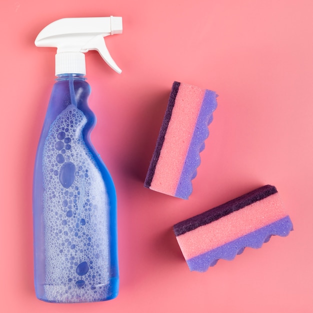 Free photo flat lay spray bottle and sponges on pink background