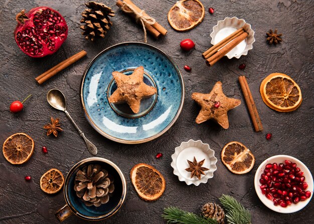 Flat lay of star-shaped cookie with pine cones and pomegranate