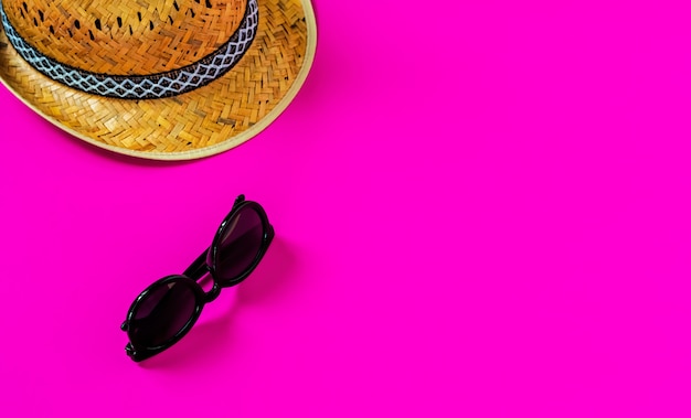 Flat lay, straw hat and sunglasses on a pink surface