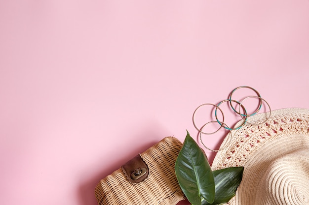 Flat lay summer composition with female accessories on pink background copy space.