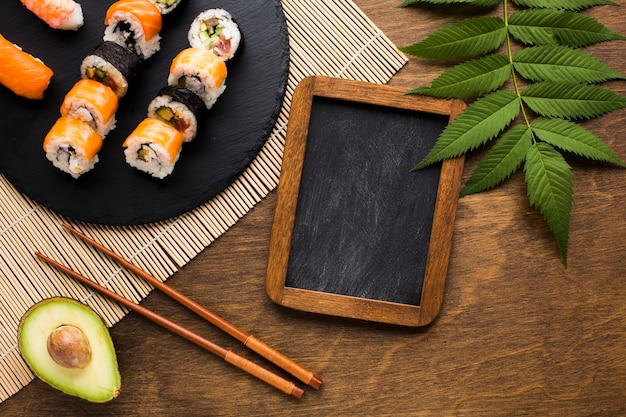 Free photo flat lay sushi arrangement with black chalkboard