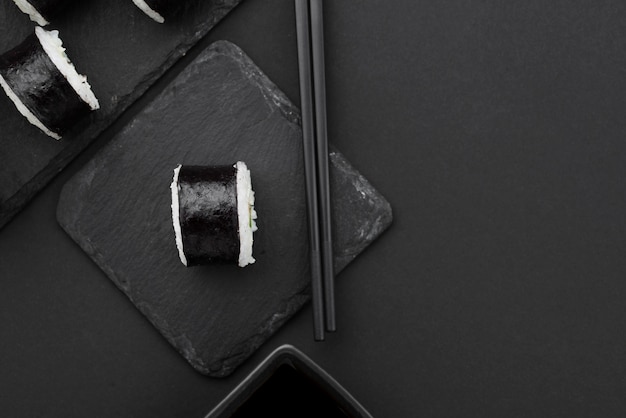 Flat lay of sushi roll on slate with chopsticks