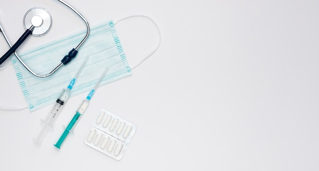 Free photo flat lay of syringes with medical mask and stethoscope