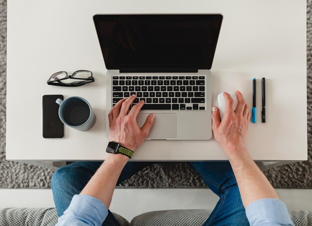 Flat lay on table workplace closeup man hands at home working typing on laptop