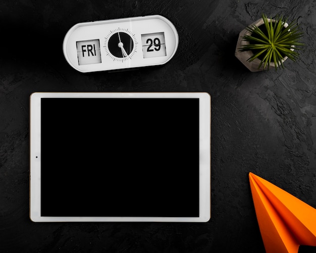 Free photo flat lay of tablet clock and paper plane