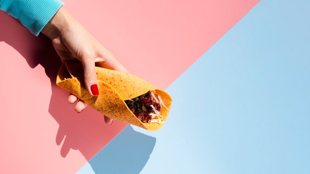 Flat lay taco with meat and veggies held in hand