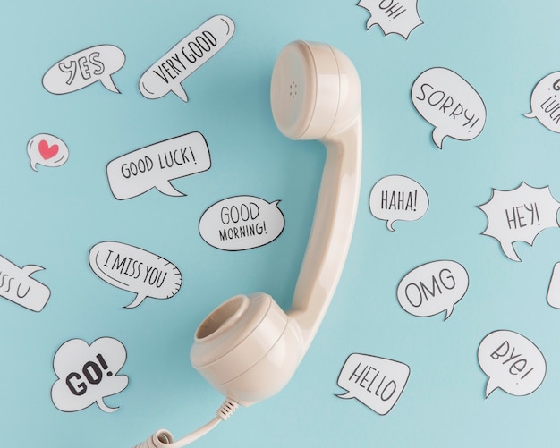 Free photo flat lay of telephone receiver with chat bubbles