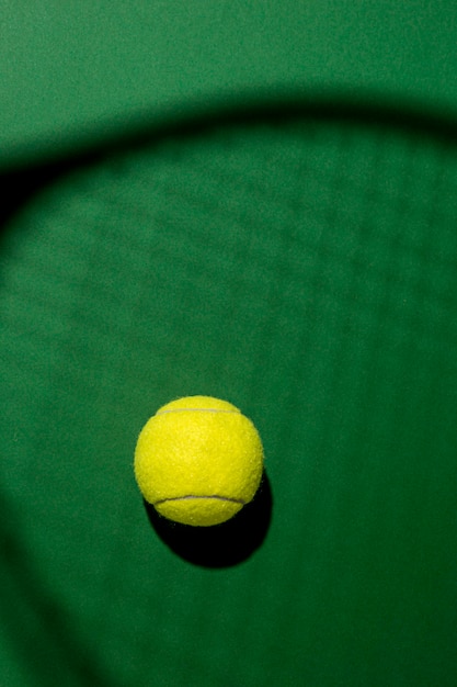 Free photo flat lay of tennis ball with racket shadow