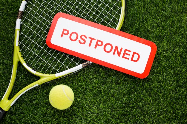 Flat lay tennis elements arrangement with postponed sign