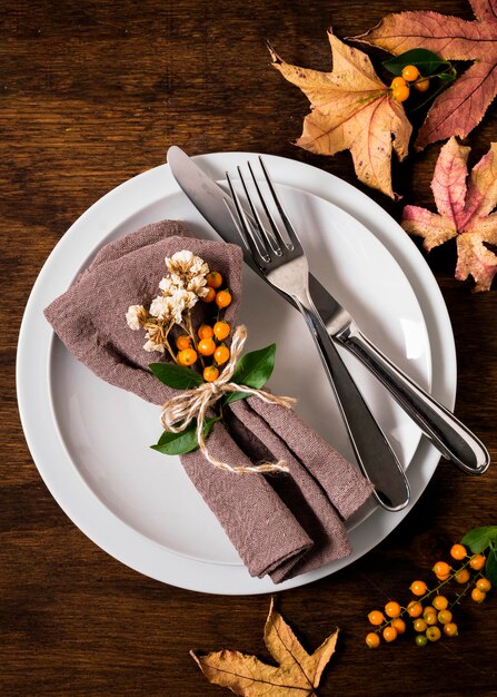 Flat lay of thanksgiving table arrangement with cutlery and autumn leaves