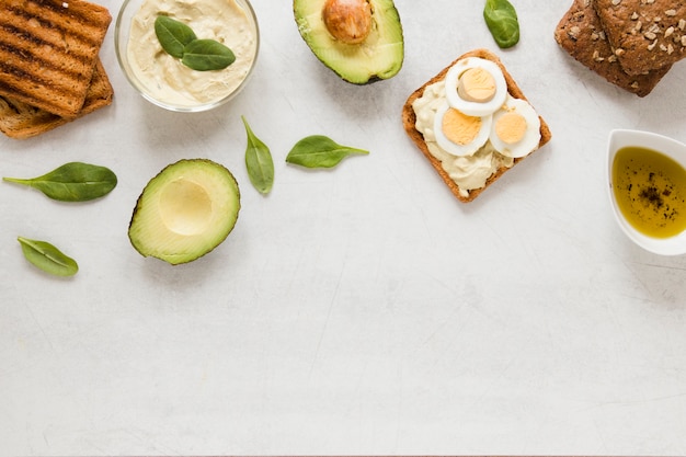 Бесплатное фото Плоский тост с яйцами хумуса и авокадо с копией пространства