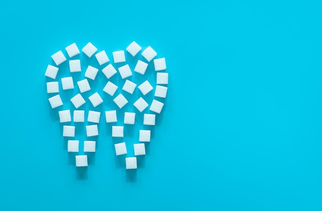 Flat lay tooth made of sugar on a blue background