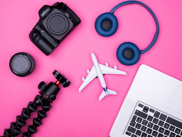 Flat lay top view of traveler photographer accessories on pink background. passport, notebook. headphones,. tripod