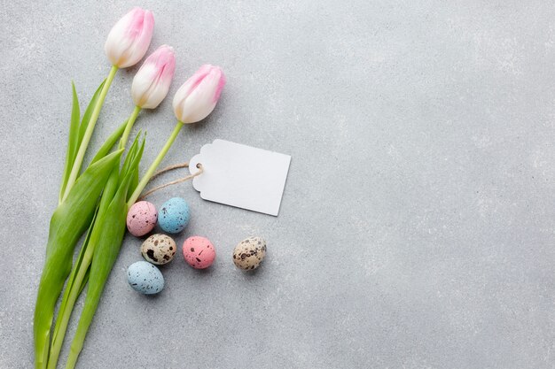 Flat lay of tulips with tag and colorful easter eggs