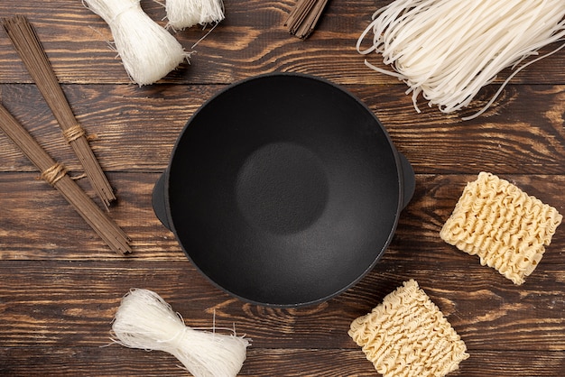 Flat lay uncooked assortment of noodles on wooden background with plate