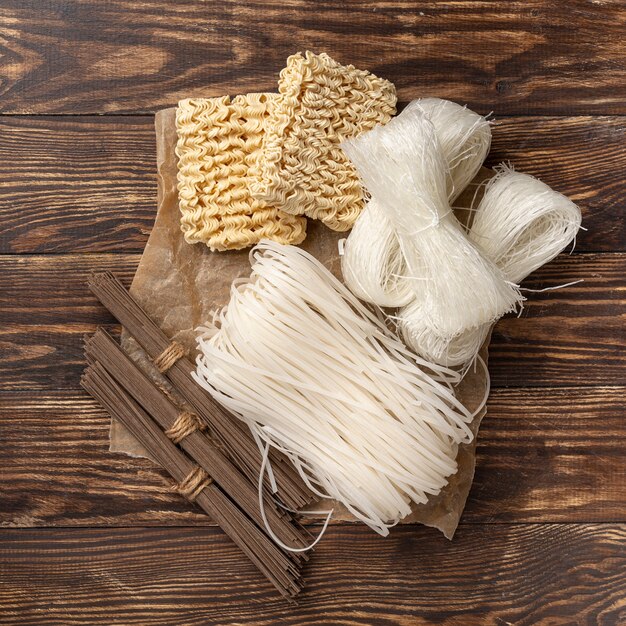 Flat lay uncooked assortment of noodles on wooden background