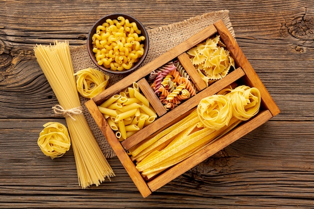 Flat lay uncooked pasta mix in wooden box