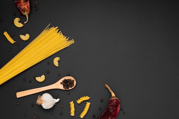 Flat lay uncooked pasta with wooden spoon ingredients and copy space
