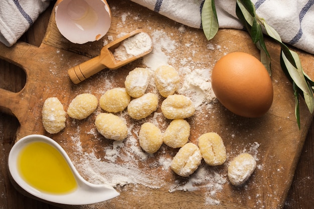 Flat lay uncooked potato gnocchi on cutting board with eggs