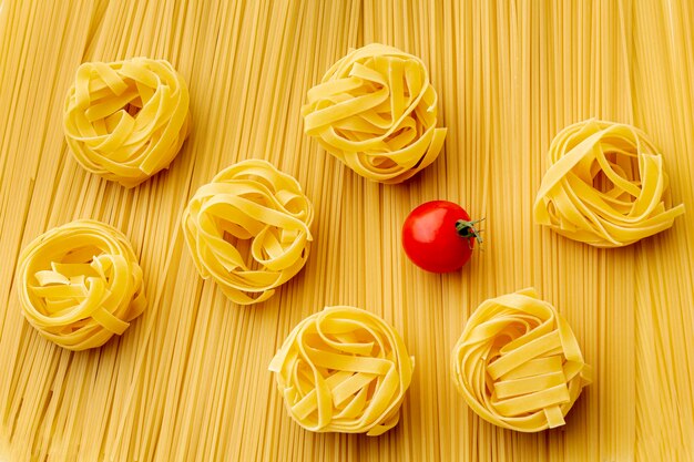 Flat lay uncooked spaghetti tagliatelle and tomatoes