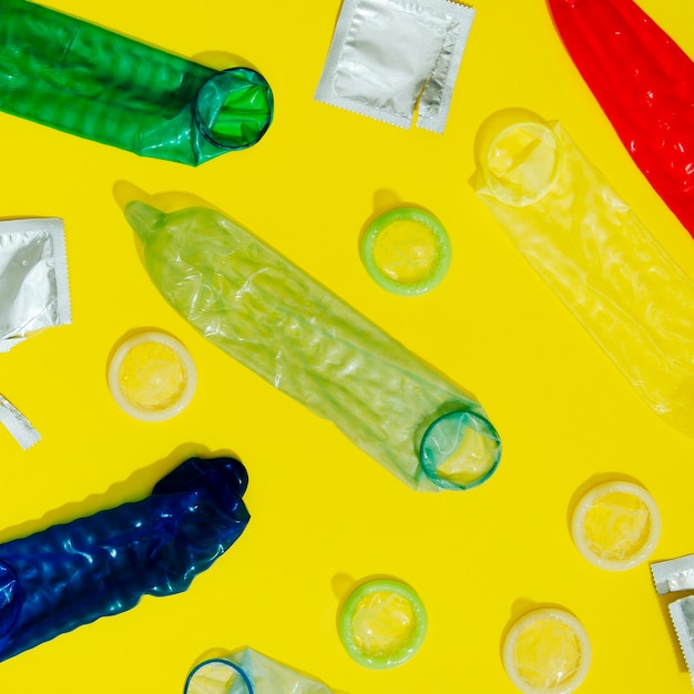Бесплатное фото Плоские лежали развернутые презервативы на желтом фоне