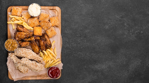 Free photo flat lay of variety of fried chicken with sauces and copy space