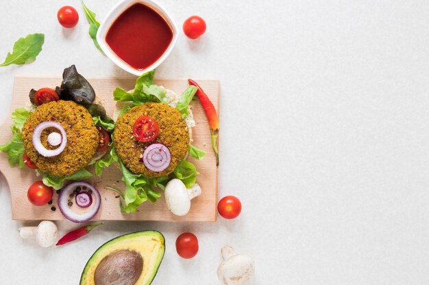 Flat lay vegan burgers on wooden board with copy space