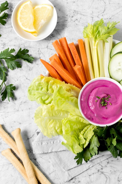 Flat lay of vegetables and pink sauce with grissini