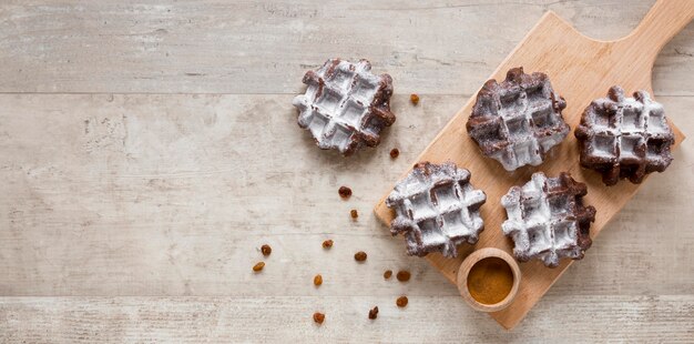 Free photo flat lay of waffles on chopping board with raisins and copy space