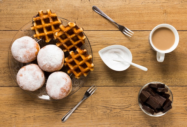 Piatto disteso di cialde e ciambelle con caffè e cioccolato