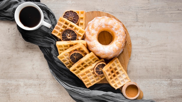 Flat lay of waffles on plate with donut and dried citrus