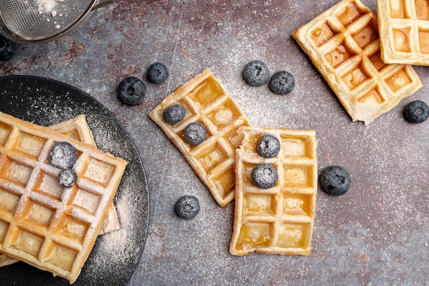 Flat lay of waffles with powdered sugar on top and blueberries