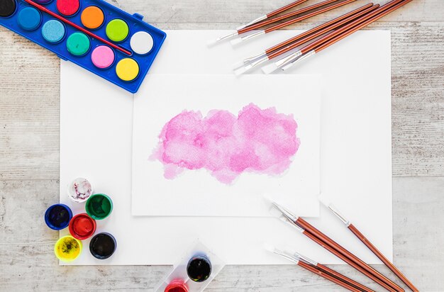 Flat lay watercolor paint and splash of pink color