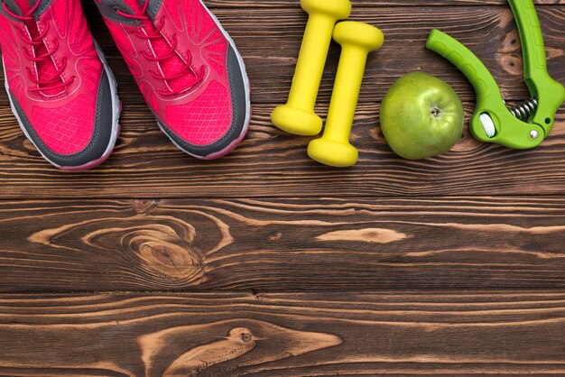 Flat lay of weights with sneakers and apple