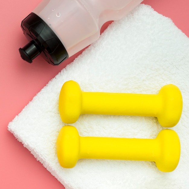 Free photo flat lay of weights with towel and water bottle