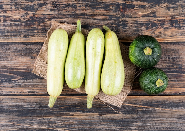 Flat lay white and green zucchinis on dark wooden table