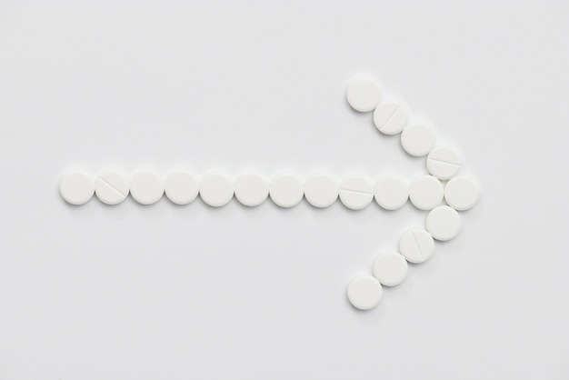 Flat lay white pills arrow